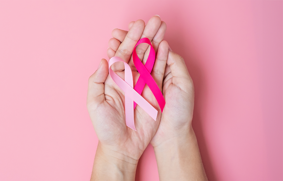 Hands holding pink and white cancer awareness ribbons