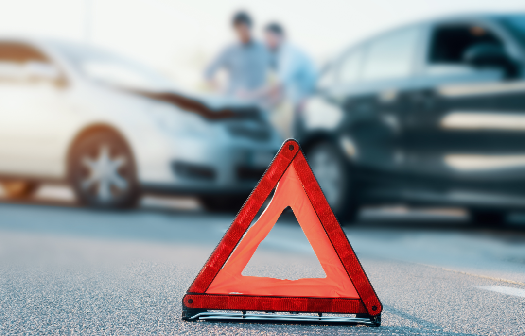 red warning triangle on road with blurred car accident in background