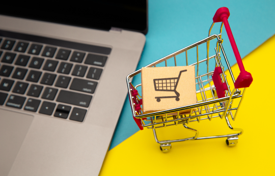 bir laptop yanında maket alışveriş arabası ve içinde maket koli