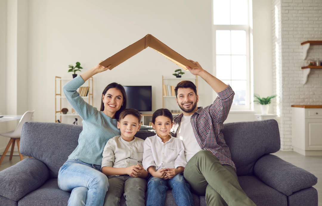 Aile evde otururken karton çatı ile korunmayı simgeliyor