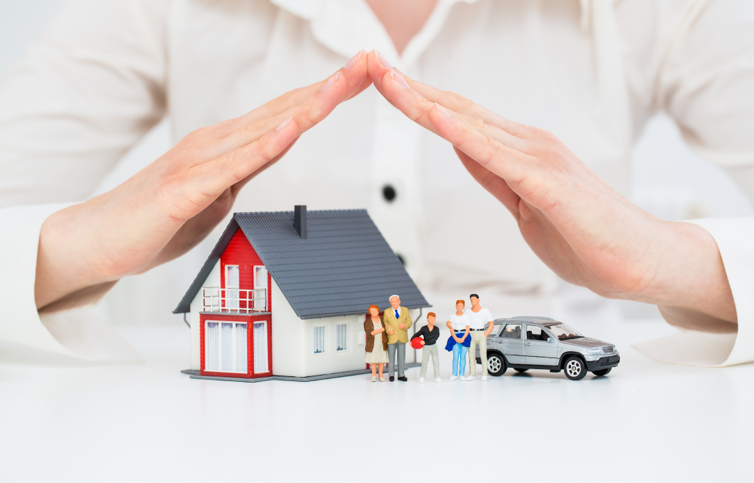 Hands forming a roof over a house family and car symbolizing insurance