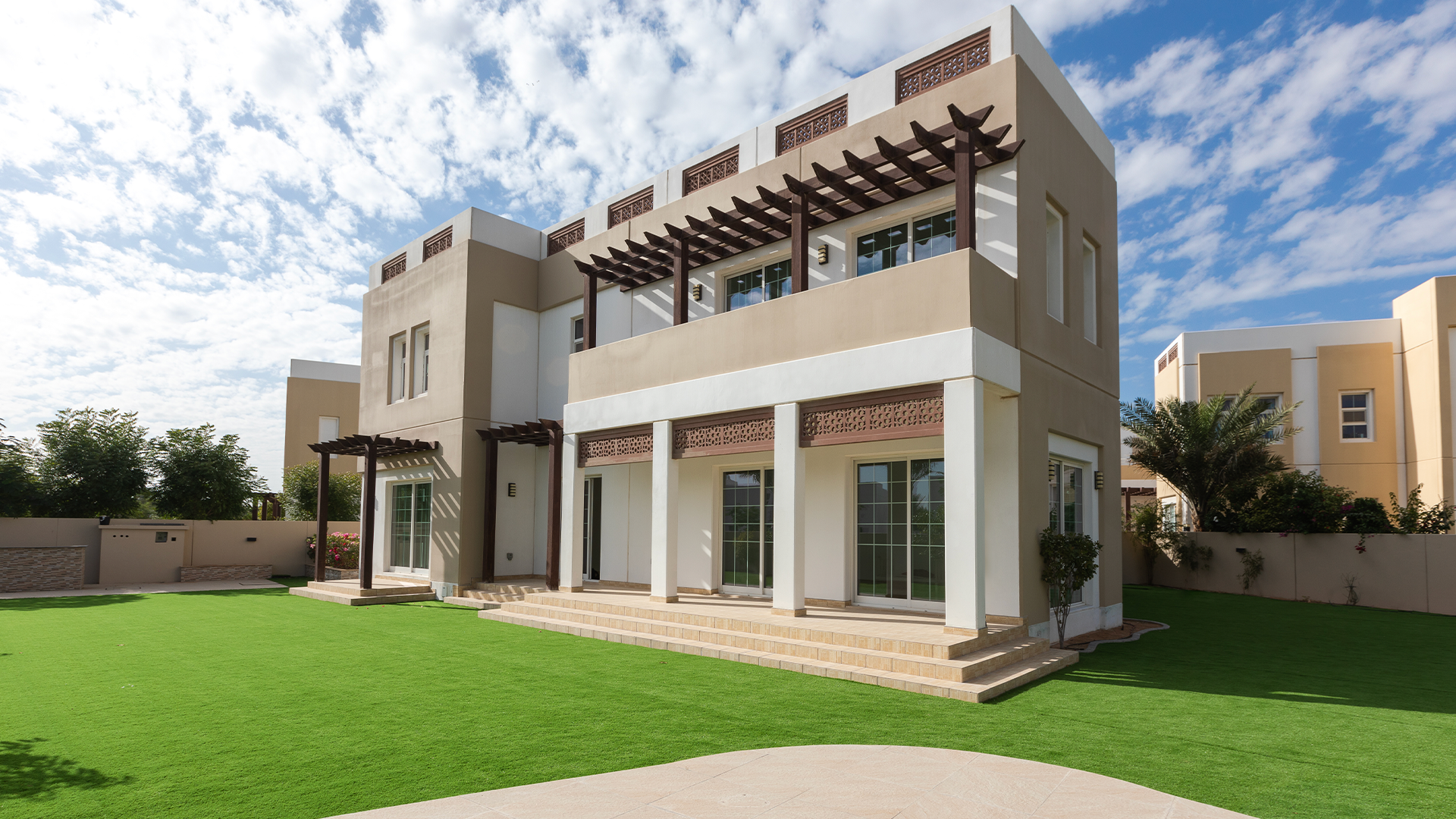 A two-story white villa with a large lawn