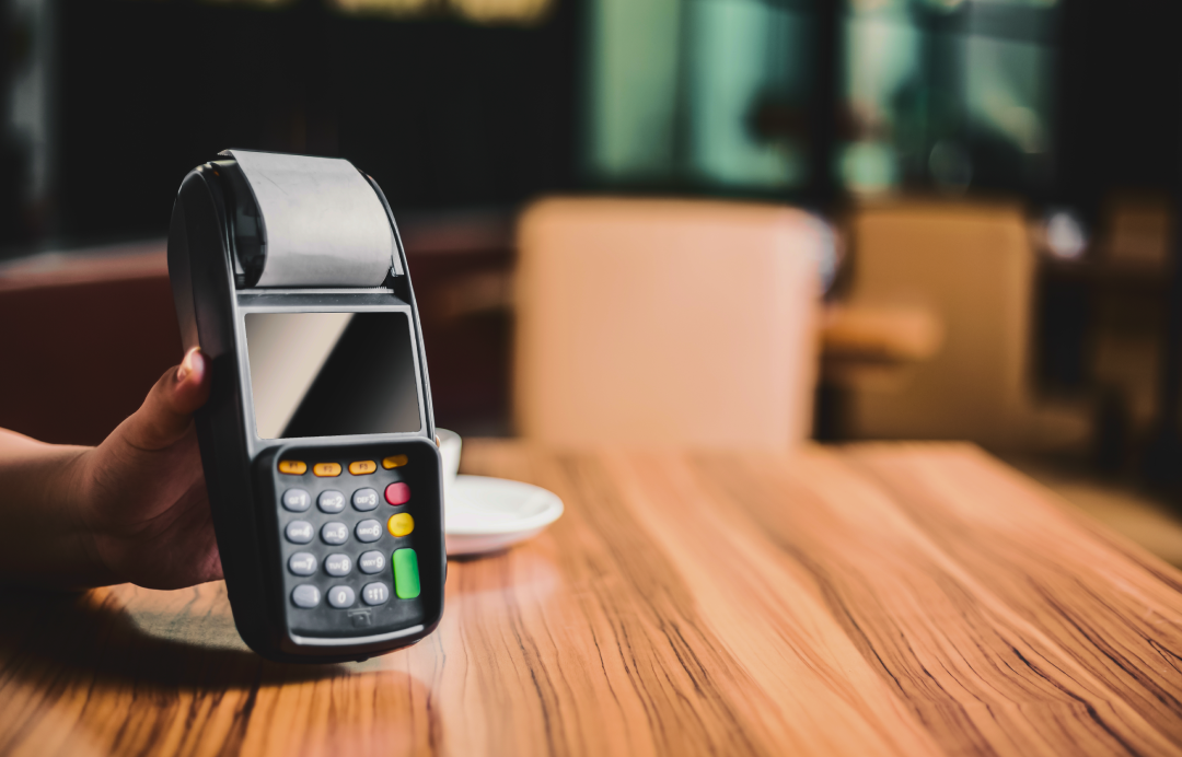 hand holding a card payment terminal on a table