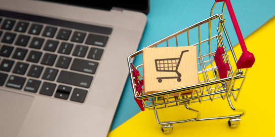 bir laptop yanında maket alışveriş arabası ve içinde maket koli