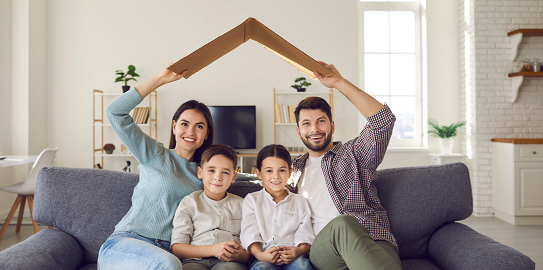Aile evde otururken karton çatı ile korunmayı simgeliyor