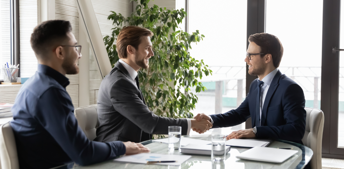 Three businessmen shaking hands in the meeting room