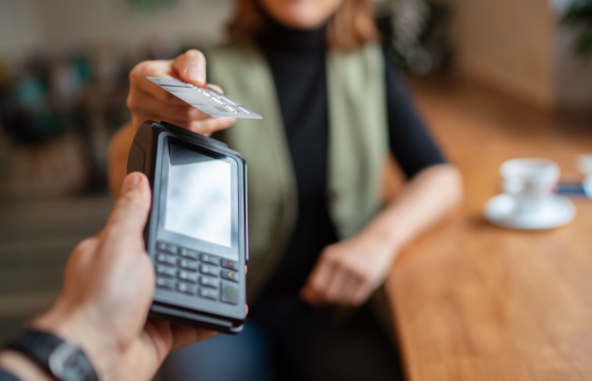 Person paying with card at a handheld payment terminal