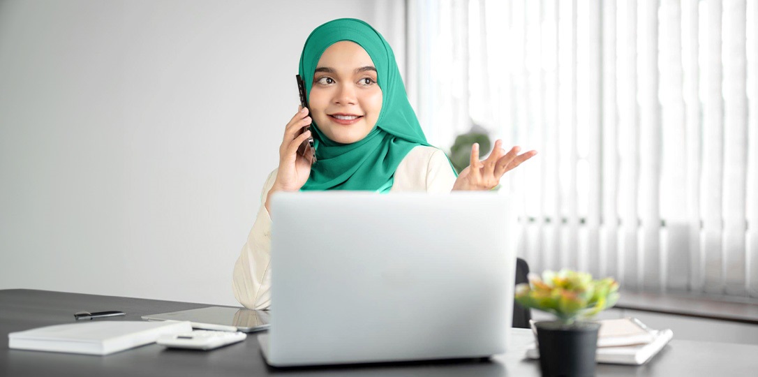 bilgisayar başında telefonla konuşan kadın