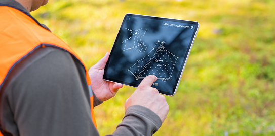 Tablet üzerinde harita ve plan inceleyen kişi